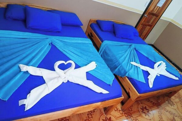 Two wooden beds with blue bedding and heart-shaped towels.