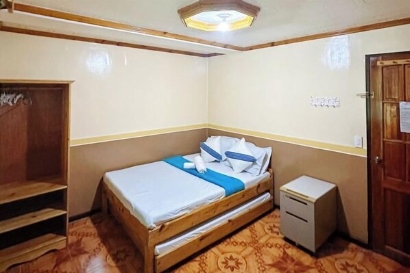 A small bedroom with a bed, a wooden wardrobe, a desk, and a door. - RedDoorz @ Bilza Lodge Sagada (Sagada)