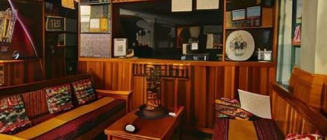 A cozy room with a wooden sofa, a small table, and shelves with various items.