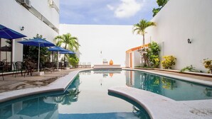 A swimming pool with lounge chairs and umbrellas, surrounded by white walls and greenery. - Mérida Centro Retreat w/ Outdoor Pool, Garden Views & Walkable Cultural Hotspots (Mérida)