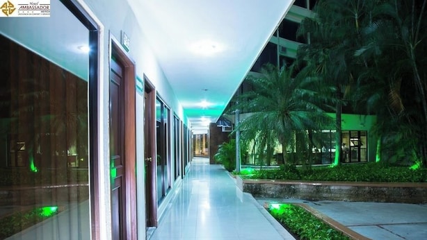 A hotel corridor with glass doors, a tiled floor, and green-lit palm trees. - Mérida Centro Retreat w/ Outdoor Pool, Garden Views & Walkable Cultural Hotspots (Mérida)