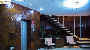 A lobby with a stone wall, a staircase, and two chairs. - Soak Up the Sun in Mérida Centro with Pool Access & Close to Local Experiences (Mérida)