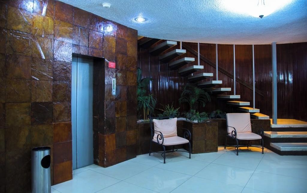 A lobby with a stone wall, a staircase, and two chairs.