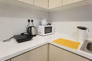 Een moderne keuken met een magnetron, koffiezetapparaat en waterkoker op het aanrecht.