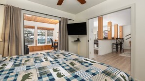 A bedroom with a large bed, a ceiling fan, a TV, and a view of the outside. - Cozy Slope Slide Granby Condo (Granby)