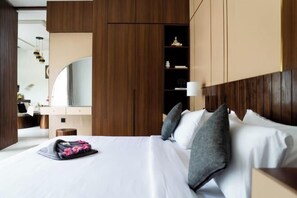 Una habitación de hotel con cama, mesita de noche, espejo y armarios de madera.