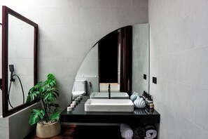 A bathroom with a white sink, a mirror, a potted plant, and a towel rack. - VIP Villas and Wellness Resort in Kuta Lombok (Pujut)