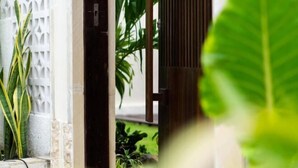 Une porte d’entrée ornée d’un motif en treillis blanc, qui donne sur un jardin planté de différentes espèces.