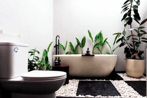 Un baño con inodoro, bañera y dos plantas en macetas.