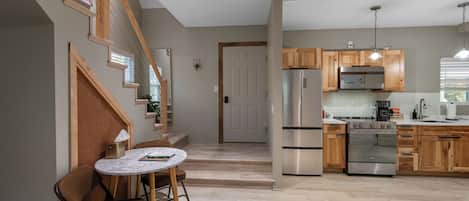 Une cuisine moderne avec des meubles en bois, des appareils en acier inoxydable et une table à manger en marbre.