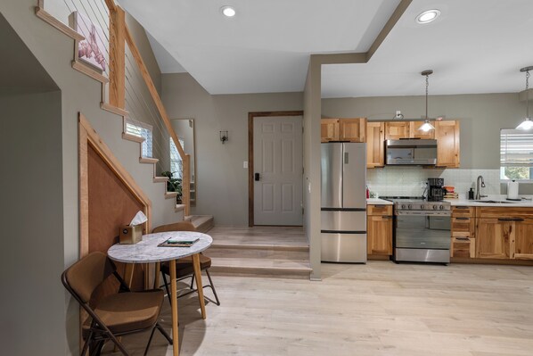 A modern kitchen with wooden cabinets, stainless steel appliances, and a marble dining table.