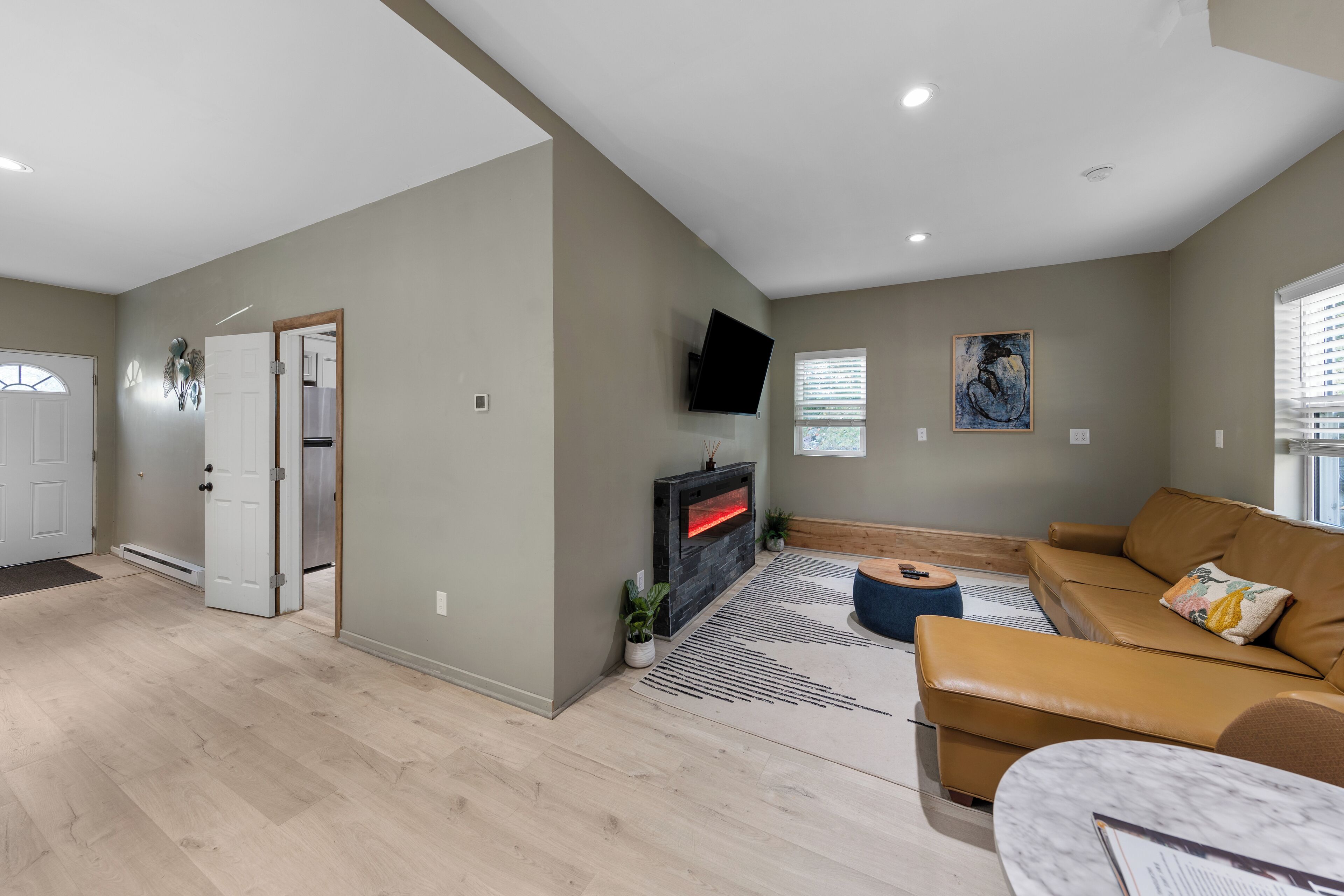 A spacious living area with a fireplace, a sofa, and a television mounted on the wall.