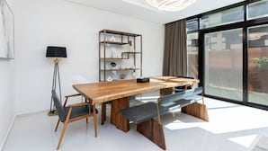 Un espace repas moderne avec une table en bois, deux chaises, un banc et un lampadaire.