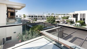 Un immeuble résidentiel moderne doté d’un balcon en verre, d’un espace extérieur aménagé et offrant une vue dégagée sur le quartier.