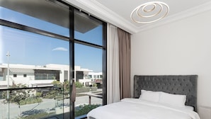 Une chambre moderne avec un grand lit, une vue sur la ville et un mur en verre.