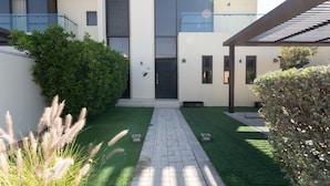 Une maison moderne à deux étages, dotée d’une entrée centrale, d’un patio couvert et d’une pelouse bien entretenue.
