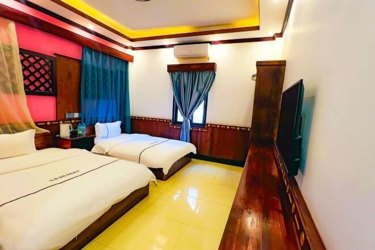 Une chambre d’hôtel avec deux lits, une télévision et un appareil de climatisation.
