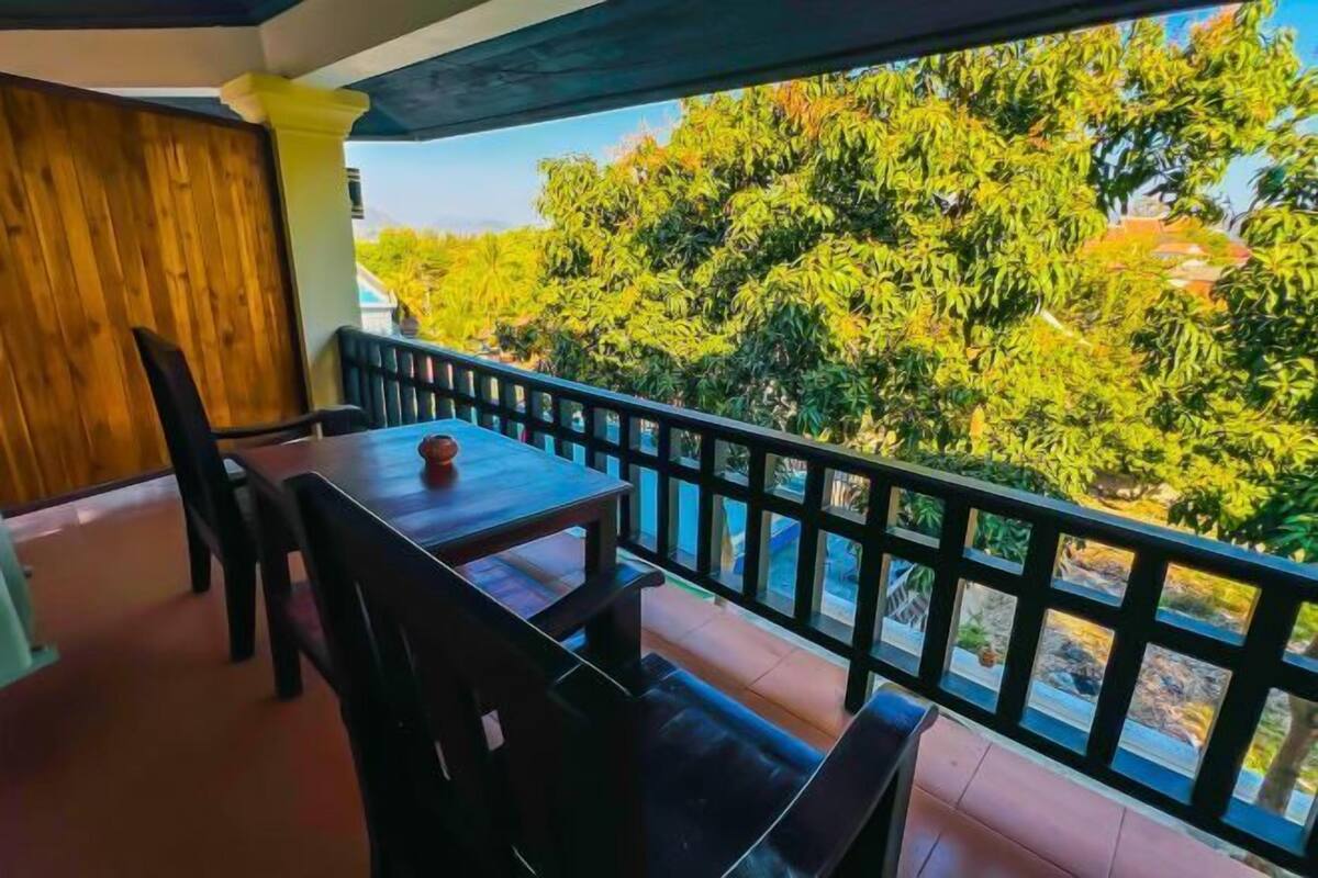 Un balcon avec une table et des chaises, donnant sur un paysage verdoyant et luxuriant.