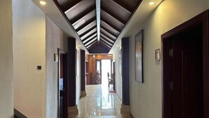 A hallway with a sloped ceiling, wooden beams, and a polished floor.