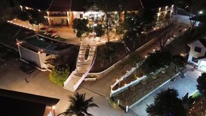 A hotel with a swimming pool, outdoor seating, and a staircase leading to the upper levels.
