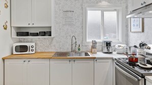 A modern kitchen with white cabinetry, a microwave, a sink, a toaster, and a stove. - SF Coast Work/Play/Hike + HotTub (Daly City)