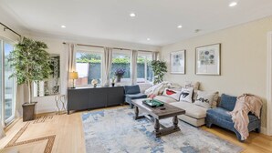 A spacious living room with a sofa, coffee table, and potted plants. - SF Coast Work/Play/Hike + HotTub (Daly City)