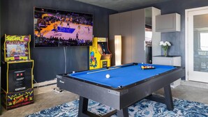 A pool table with a blue felt surface, a large flat-screen TV displaying a basketball game, and arcade games including 'Street Fighter II' and 'Pac-Man' in a room with dark walls and a patterned rug. - SF Coast Work/Play/Hike + HotTub (Daly City)