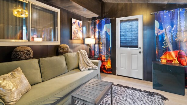 A modern living room with a sofa, a coffee table, and a door with a decorative curtain.