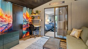 A modern room with a bed, a desk, and a sofa. There is a sign on the wall that says "NAPS FIX EVERYTHING".