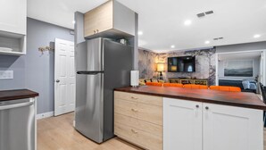 A modern kitchen with a stainless steel refrigerator, wooden cabinets, and a wooden countertop.