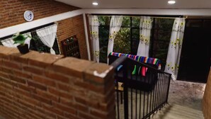 Un balcón con un muro de ladrillo, una barandilla de metal negro y un paño a rayas de colores colgado de la barandilla.