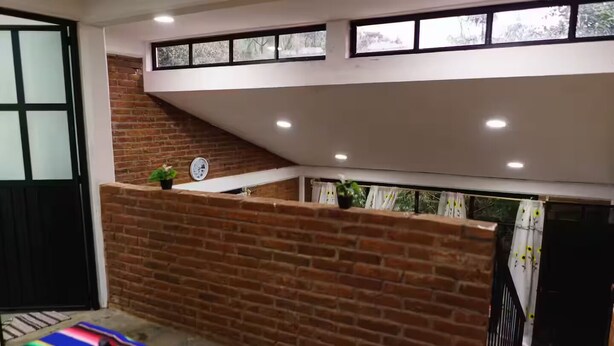 Una habitación con pared de ladrillo, ventana e iluminación empotrada en el techo.