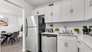 A modern kitchen with white cabinets, stainless steel appliances, and a dishwasher. - North Miami 2BR | Pool + Free Parking (North Miami)