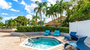 A swimming pool with lounge chairs, surrounded by palm trees and a white fence. - North Miami 2BR | Pool + Free Parking (North Miami)