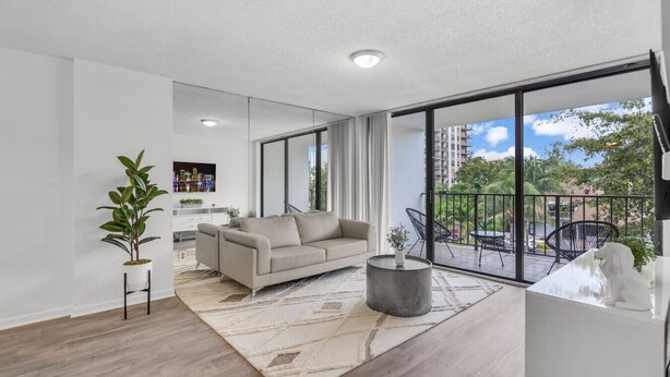 A modern living room with a sofa, a coffee table, and a potted plant. - North Miami 2BR | Pool + Free Parking (North Miami)