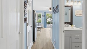 Un pasillo con comedor, un baño con tocador y espejo, y un letrero que dice 'Bébé Cottage'.