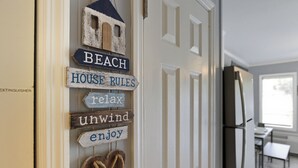 Una puerta con carteles de madera que dicen "BEACH", "REGLAS DE LA CASA", 