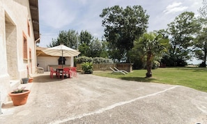 A patio area with a table and chairs, a covered seating area, and a lawn.