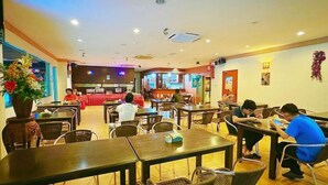 Un ristorante con diversi tavoli e sedie, alcuni dei quali occupati da clienti.
