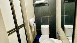 A bathroom with a toilet, a sink, a hand dryer, and a mirror.