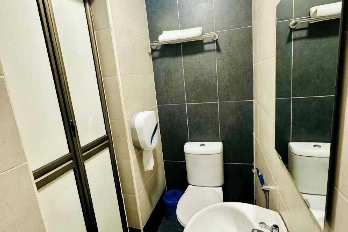Een badkamer met een toilet, een wastafel, een handdroger en een spiegel.