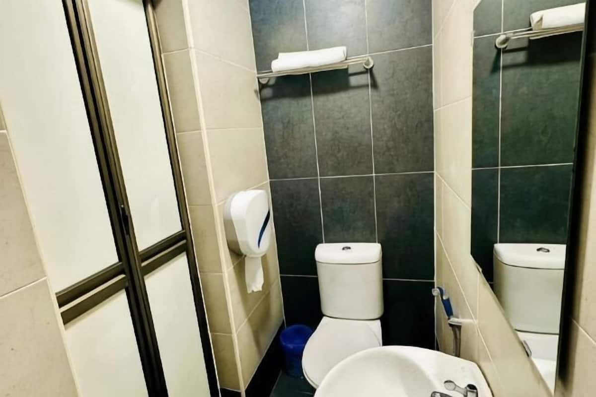 A bathroom with a toilet, a sink, a hand dryer, and a mirror.