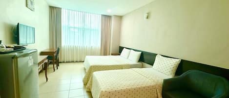 A hotel room with two beds, a desk with a chair, a television, and a refrigerator.