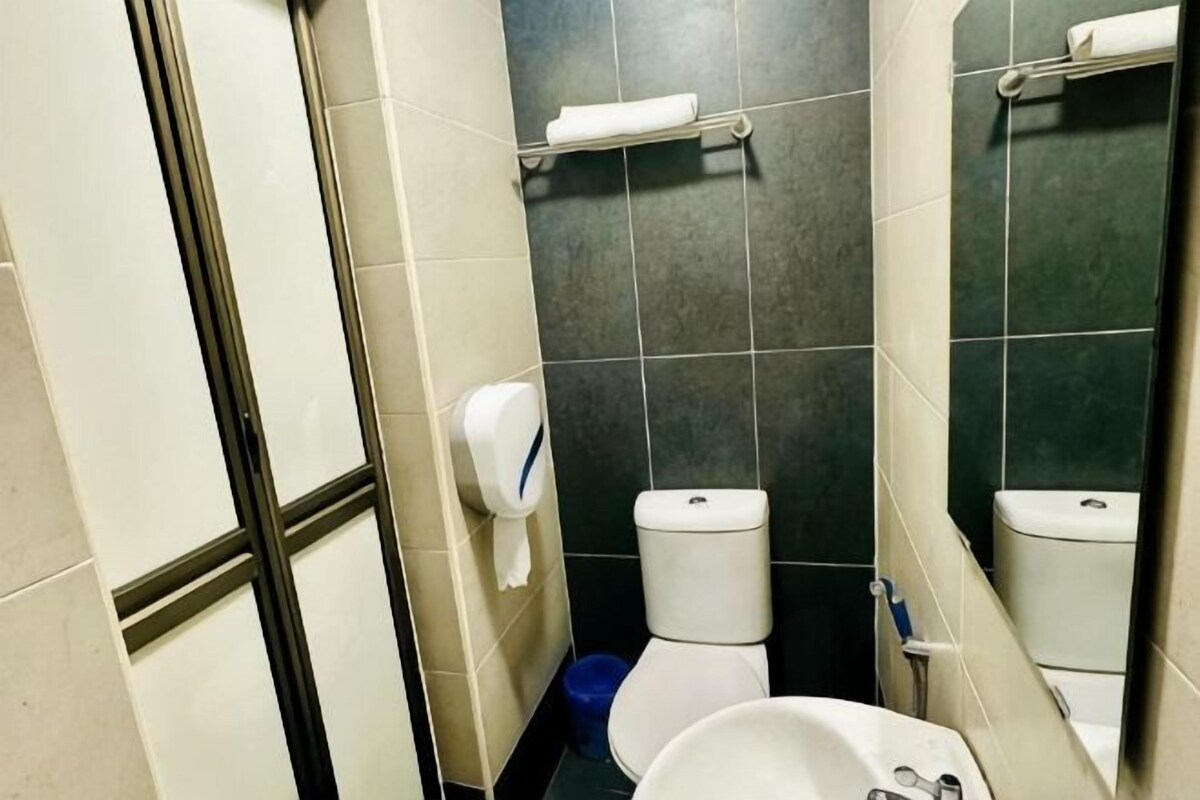 A bathroom with a toilet, a sink, a hand dryer, and a mirror.