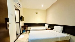 A hotel room with two beds, a desk, a chair, a television, and a door.
