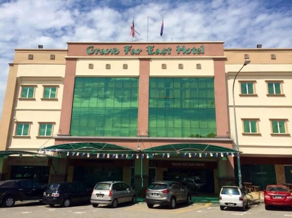 Un hôtel doté d’une grande façade en verre, d’une entrée abritée et de nombreux espaces de stationnement.