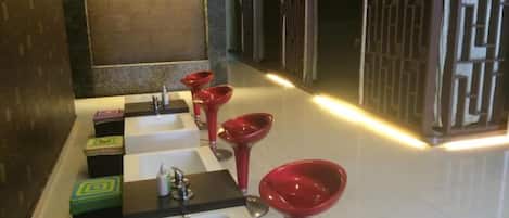 Una hilera de lavamanos con lavabos rojos y piso de baldosas.