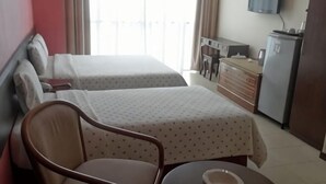 A hotel room with two beds, a chair, a small table, a TV, and a dresser.