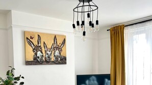 Una sala de estar moderna con comedor, un televisor de pantalla plana y un candelabro.