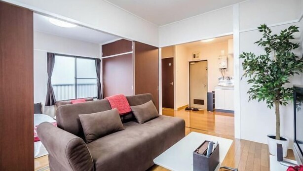A modern living room with a brown sofa, a small white table, and a potted plant.